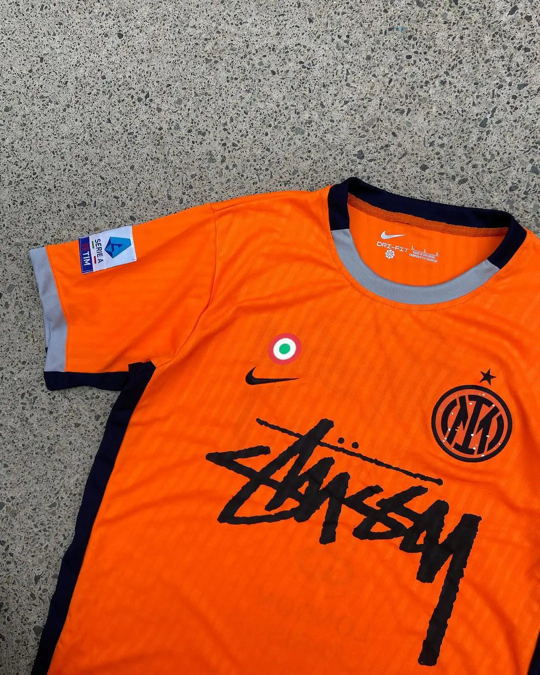 Inter Milan x Stussy Limited Edition Jersey in vibrant orange, featuring the Inter Milan crest and Stussy logo, blending football heritage with streetwear style.